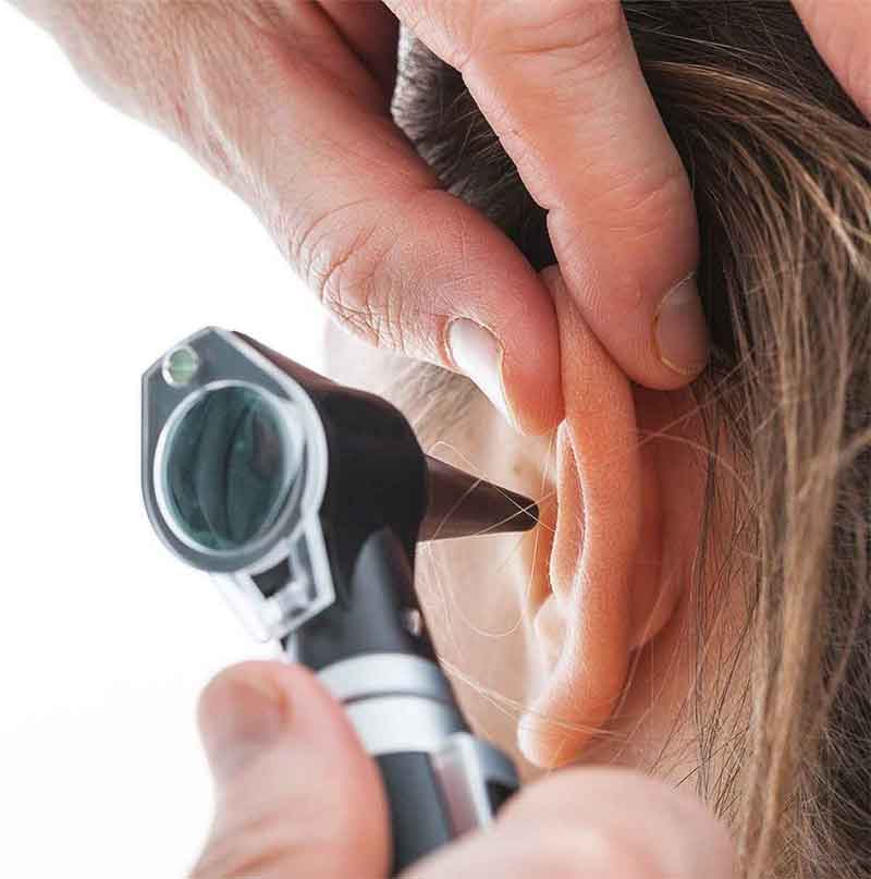 Audiologist looking in a patients ear.